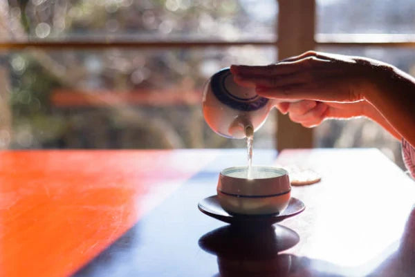 Mujer prepara té japonés en tetera tradicional japonesa de cerámica yokode kyūsu